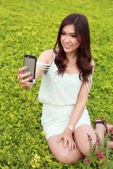 young woman taking a self portrait by using mobile phone in the garden