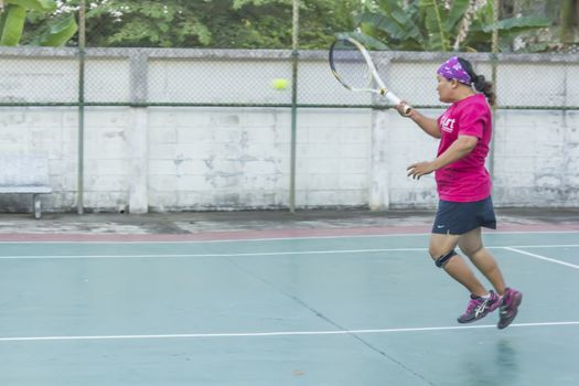 SURAT THANI, THAILAND - MARCH 1:Unidentified Thai senior woman play tennis outdoor at Chaiya tennis court on March 1, 2014 in Surat Thani, Thailand.