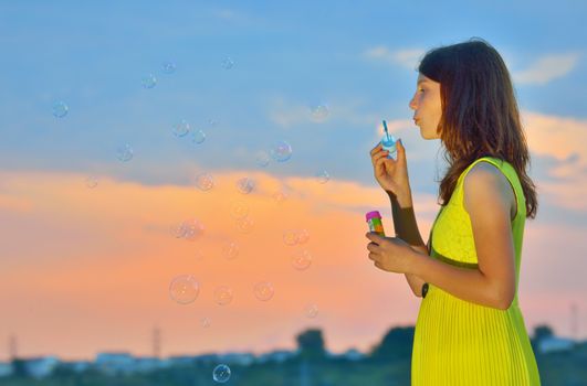 young girl with soap-bubbles in sunset