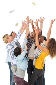 Happy group of young friends throwing money in the air on white background