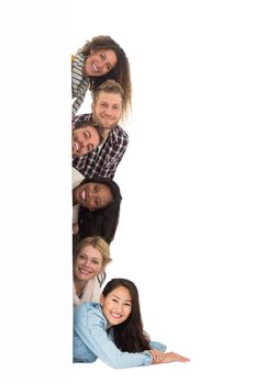 Happy group of young friends peeking from behind a wall on white background