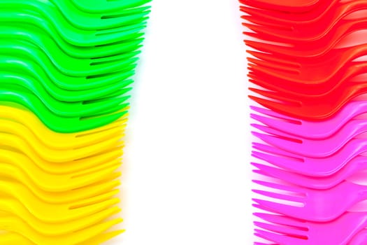Multi colored plastic cutlery on a white background