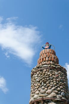 cobblestone lighthouse tower on blue sky background