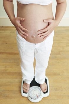 Pregnant Woman Standing On Bathroom Scales