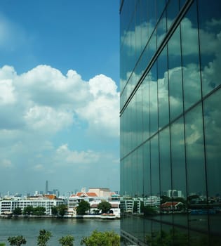 Tall buildings with modern style creating a mirror, reflecting the light from outside the building, reflecting  the clouds that floating by and the beautiful of blue sky.                               