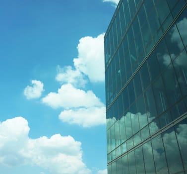 Tall buildings with modern style creating a mirror, reflecting the light from outside the building, reflecting  the clouds that floating by and the beautiful of blue sky.                                  