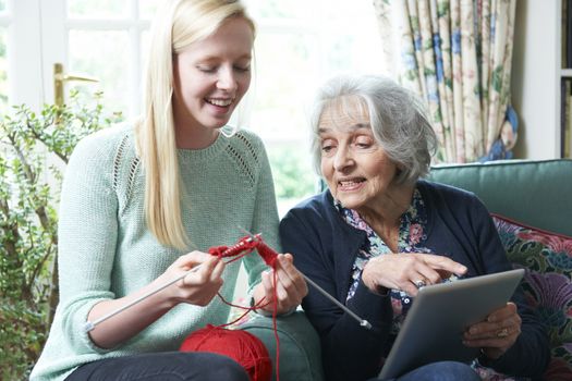 Grandmother With Digital Tablet Showing Granddaughter How To Knit