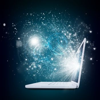 Open laptop with magic light and falling stars. Dark background