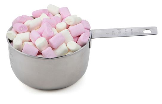 Pink and white mini marshmallows in an American cup measure, isolated on a white background