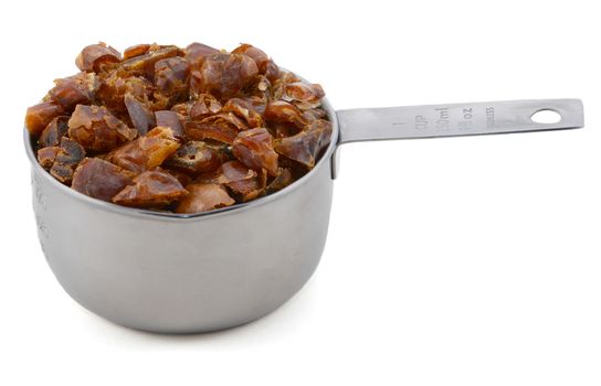 Chopped dates in an American cup measure, isolated on a white background