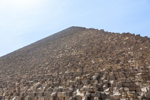 View up the side of Great Pyramid of Giza in Cairo Egypt on baking hot day with the heat haze and sun blinding the image at the top