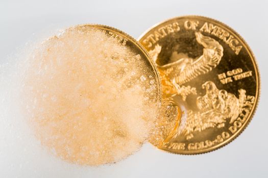 Gold eagle one ounce coin emerging from a frozen ice block to illustrate concept of gold coming out of deep freeze and price going to rise