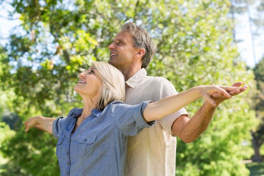 Romantic couple standing arms outstretched in park