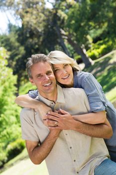 Portrait of happy couple with arm around in park