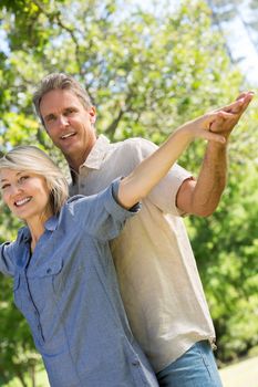 Tilt image of romantic couple with arms outstretched in park