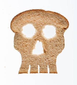 Skull shaped piece of bread cut from whole wheat loaf to illustrate danger from gluten in wheat products