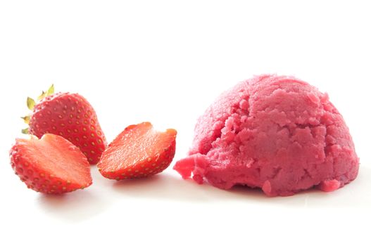 Strawberry flavoured ice cream scoop with berries on the side 
