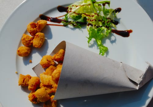 A cartridge of fried fish and some lettucce.