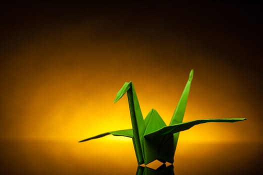 green origami paper crane with orange back light