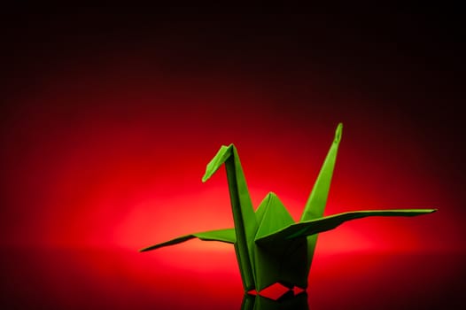 green origami paper crane with red back light