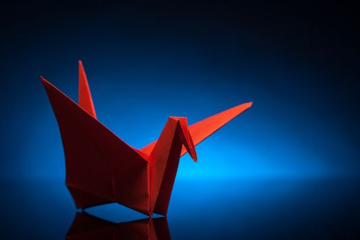 red origami paper crane with blue back light