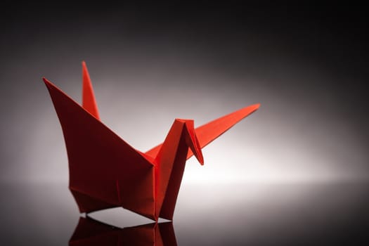 red origami paper crane with white back light