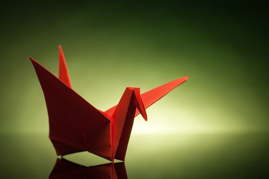 red origami paper crane with green back light
