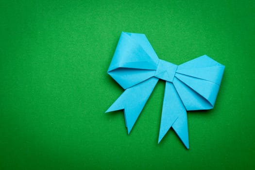 blue origami paper bow on green paper background