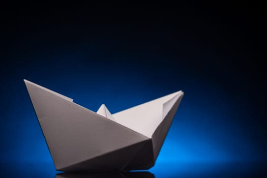 white origami paper boat with blue back light