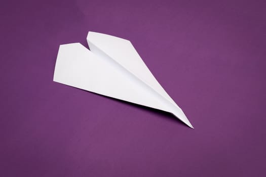 white paper plane on purple paper background