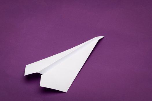 white paper plane on purple paper background