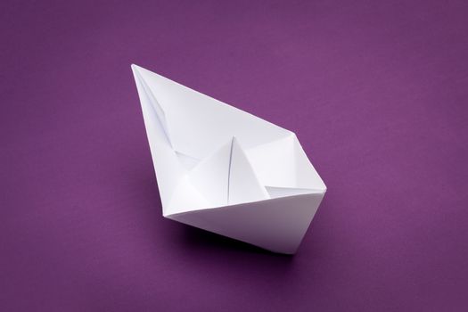 white paper boat on purple paper background