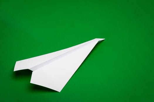 white paper plane on green paper background