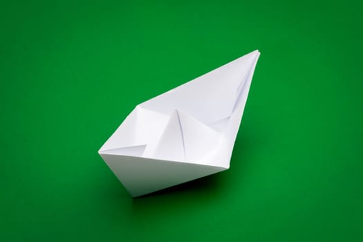 white paper boat on green paper background