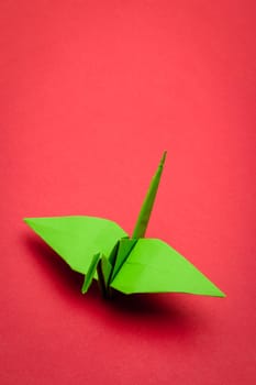 green origami paper crane on red paper background