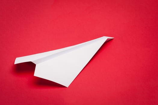 white paper plane on red paper background