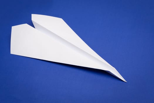 white paper plane on blue paper background