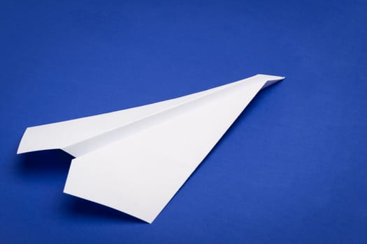 white paper plane on blue paper background