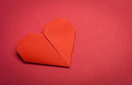 red origami paper heart on red paper background