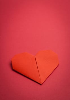 red origami paper heart on red paper background