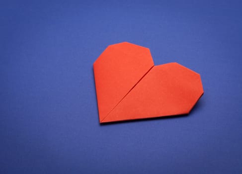 red origami paper heart on blue paper background