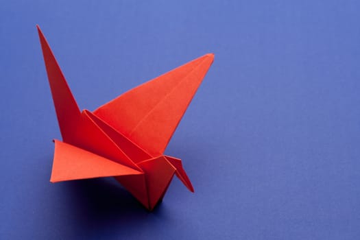 red origami paper crane on blue paper background