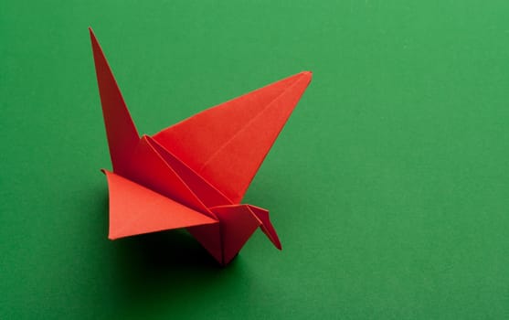 red origami paper crane on green paper background