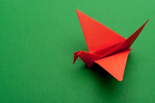 red origami paper crane on green paper background