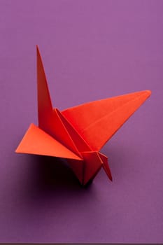 red origami paper crane on purple paper background