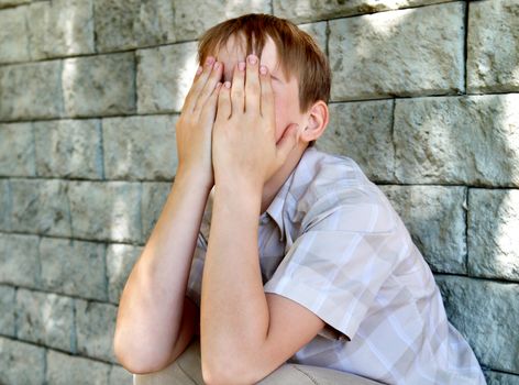 Sad and Troubled Kid sitting by the Wall