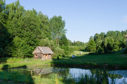 countryside with small wooden rural relaxation bathhouse and green nature in background