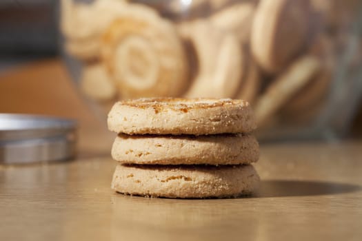 Three biscuits over a wooden table, biscuit glass vase on the back