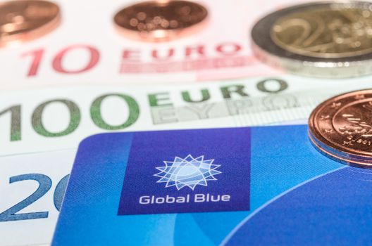 MUNICH, GERMANY - FEBRUARY 23, 2014: Closeup Tax Free plastic card from company Global Blue banknotes and coins