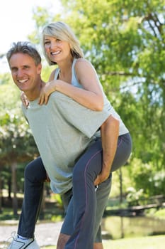 Portrait of loving man giving piggyback ride to woman in the park